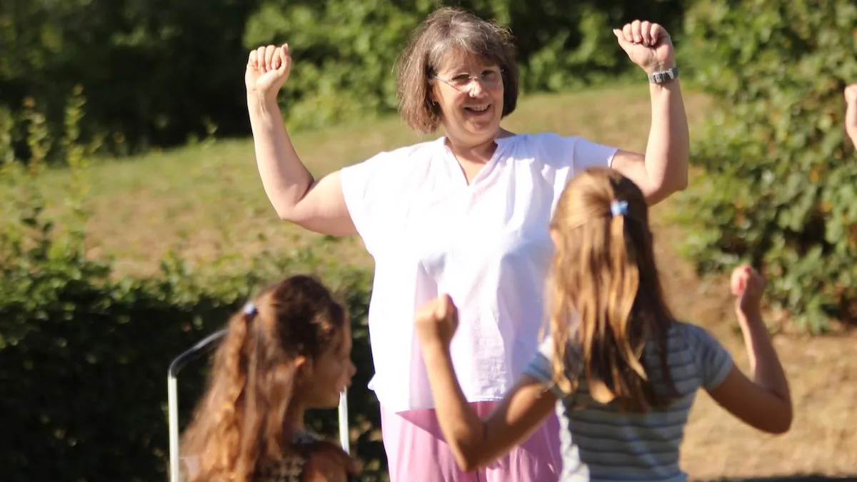 Jutta Gelbke macht mit Kindern eine Mut-Übung mit erhobenen Fäusten im Freien